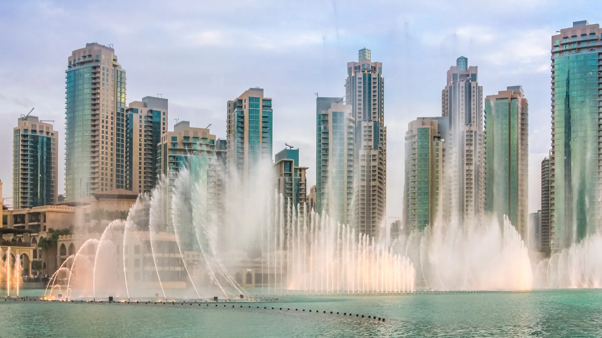Dubai Fountain show at dusk with skyline behind