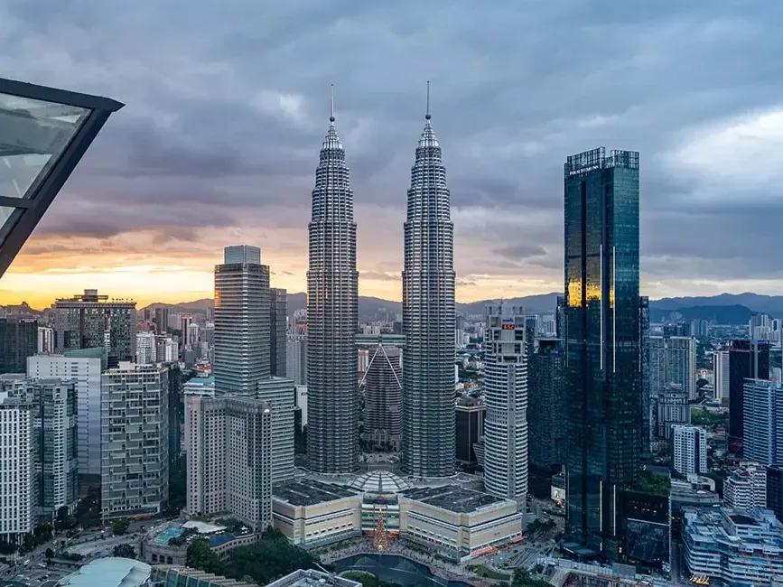 The Petronas Twin Towers rising above the Kuala Lumpur skyline at dusk