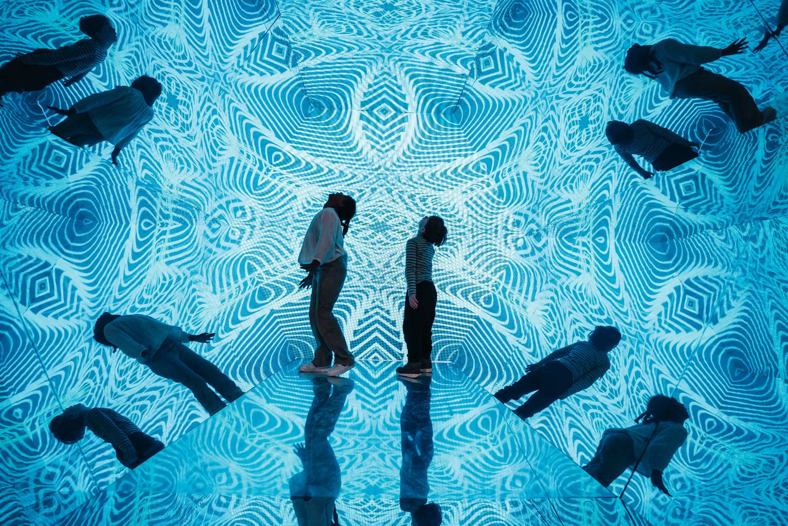 Visitors in a mirrored, patterned room at the Museum of Illusions
