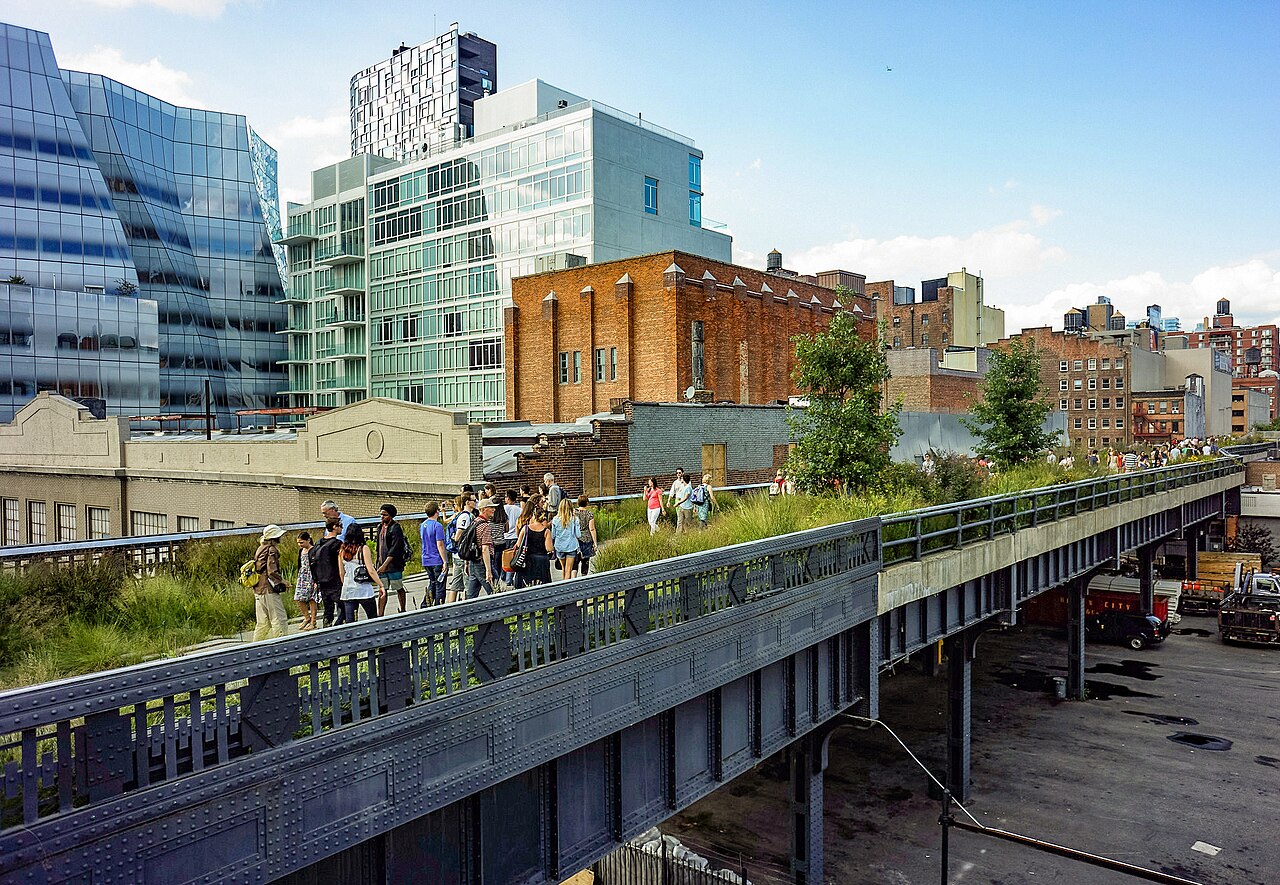 Visitors walking the elevated High Line park with city buildings behind