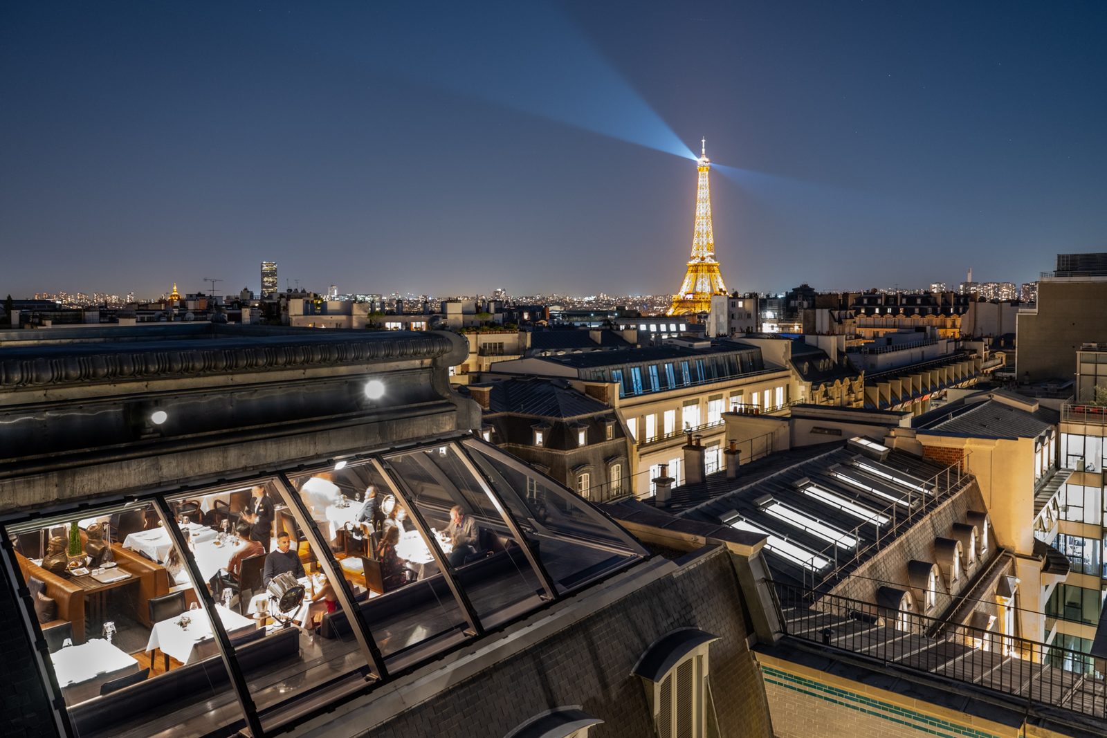 L'Oiseau Blanc rooftop restaurant with a floodlit Eiffel Tower in the background