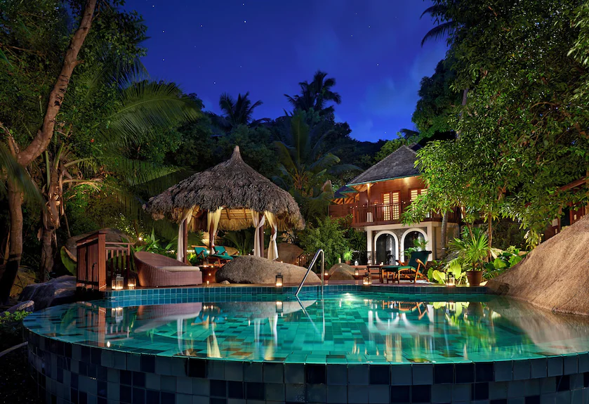 Villa pool at night surrounded by granite boulders and palms, Labriz Silhouette Island